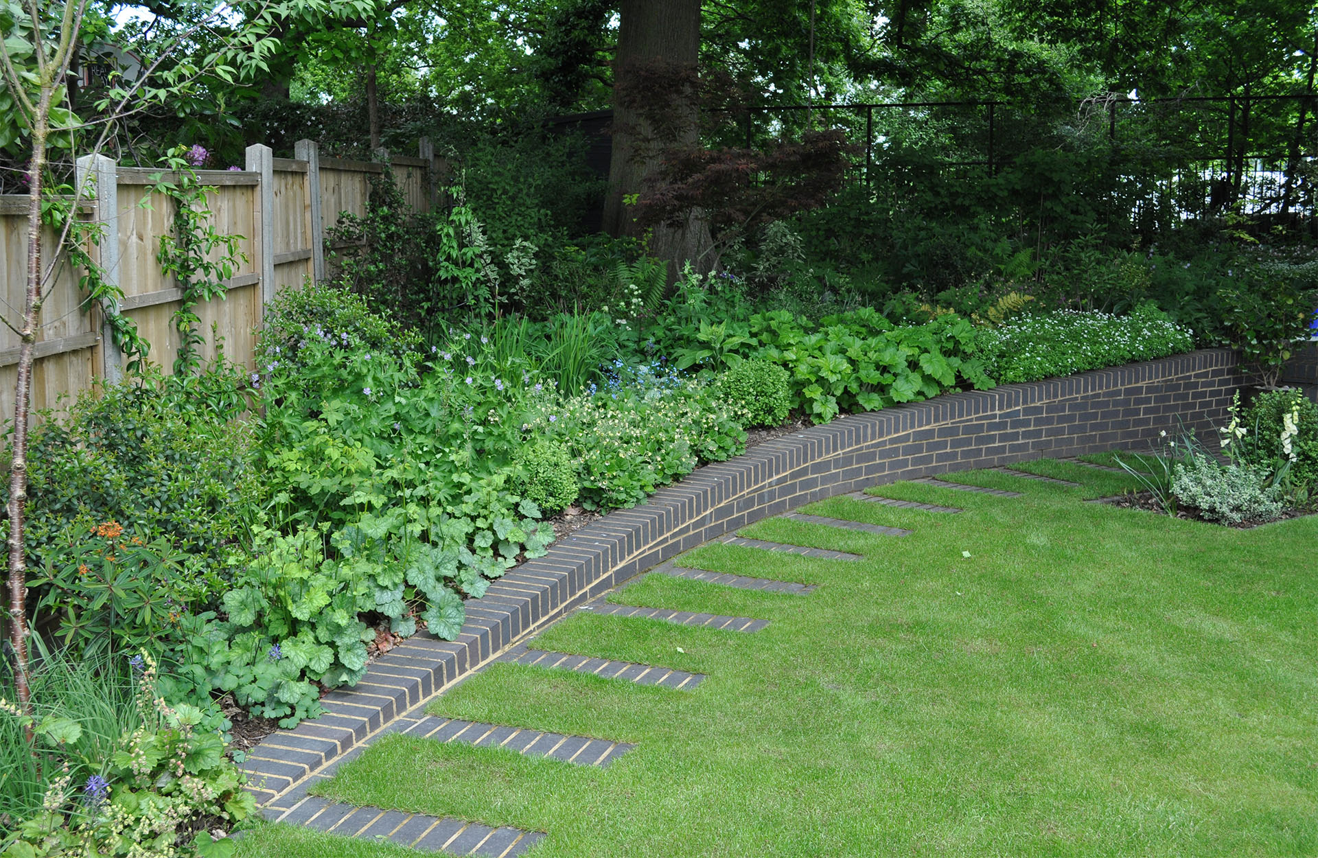 a curved retaining wall in Staffs blue brick with matching stepping stone path by designer Jilayne Rikards image by Simon Bourne